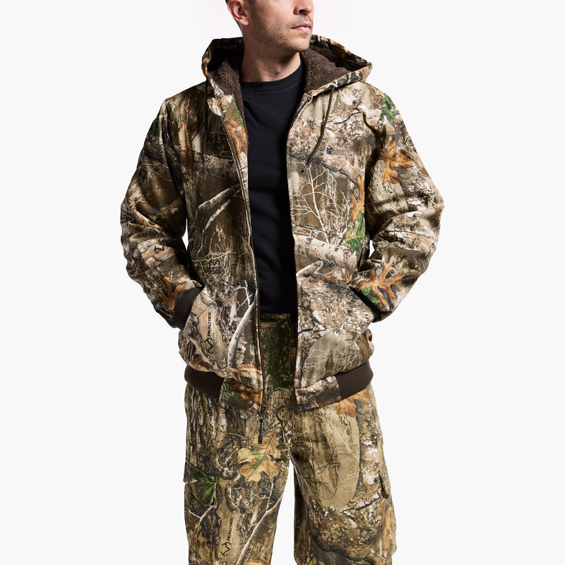 Person wearing a camouflage jacket and pants on a white background